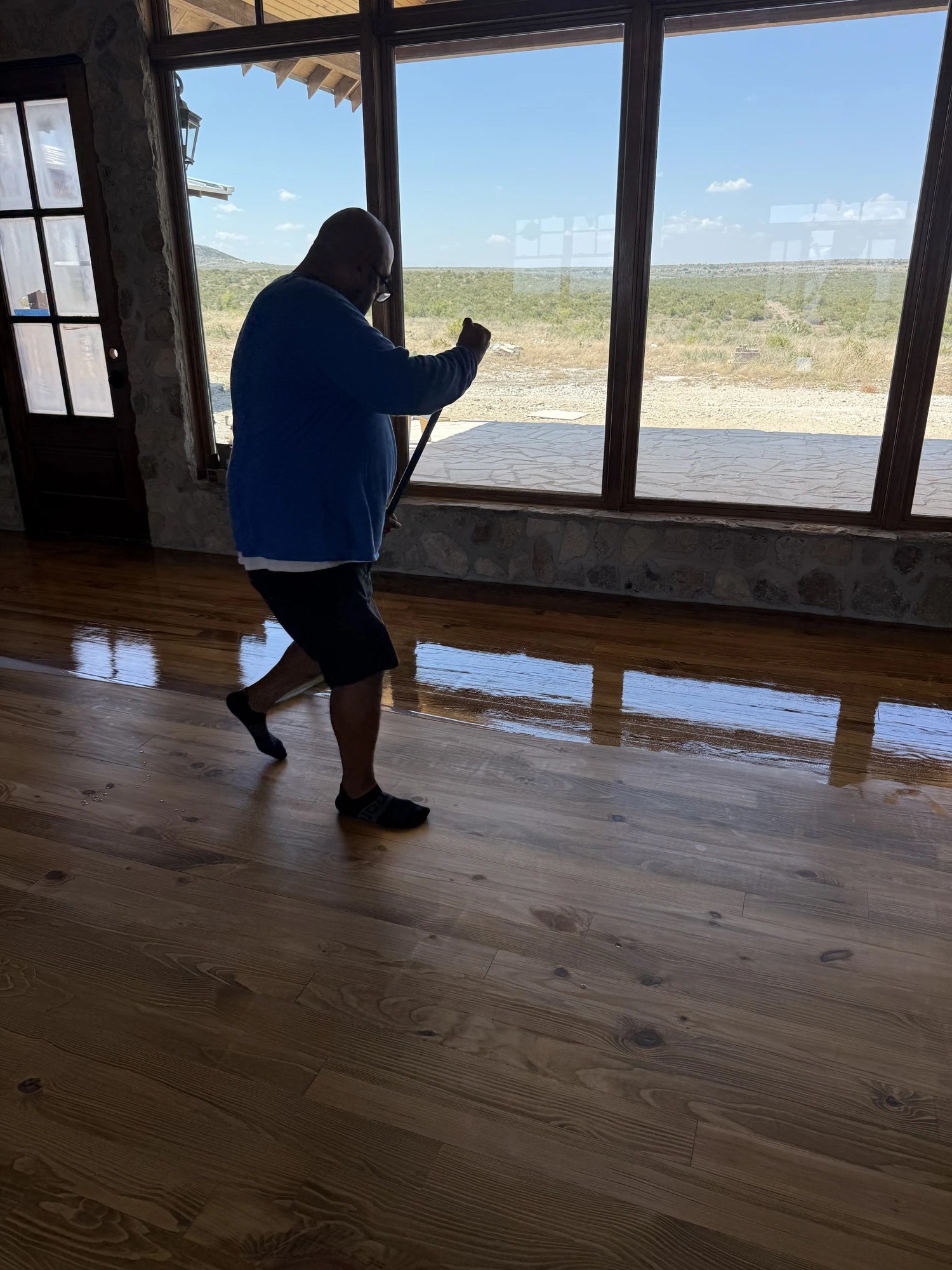 Applying a glossy finish to a hardwood floor by a picture window