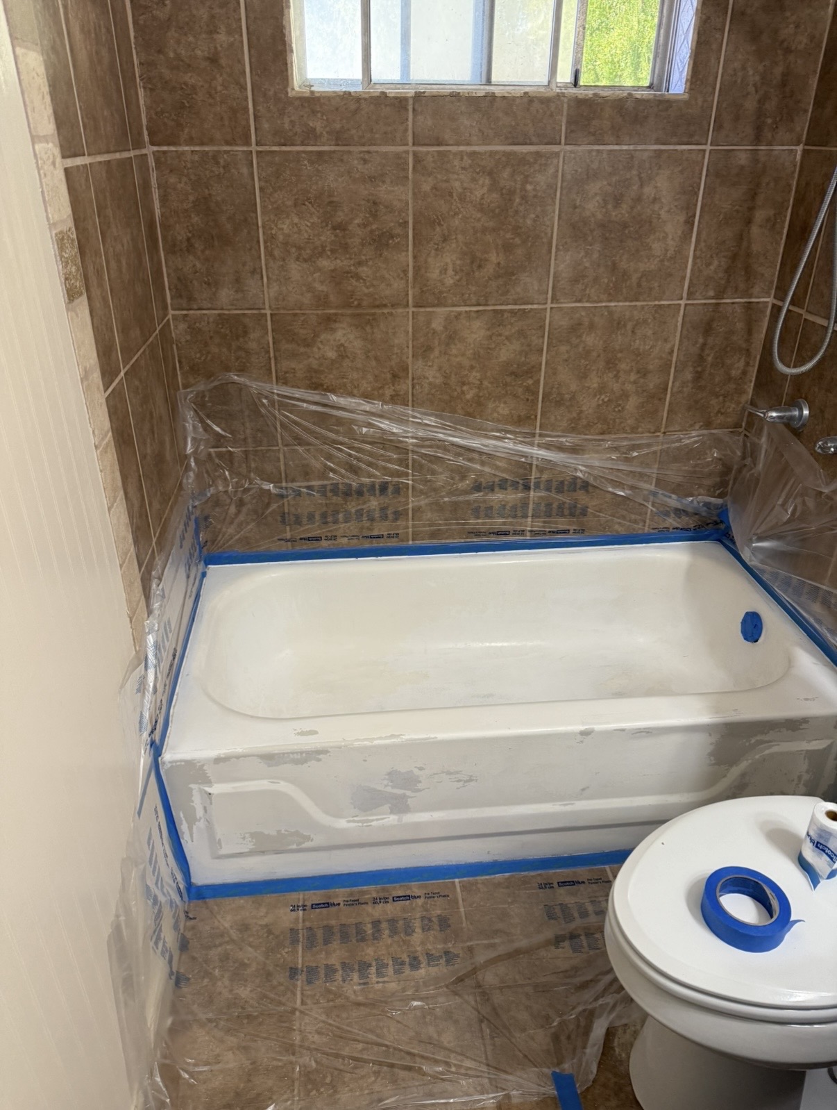 Bathtub masked and prepped with tape and sheeting for refinishing